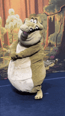 a crocodile mascot stands in front of a forest backdrop