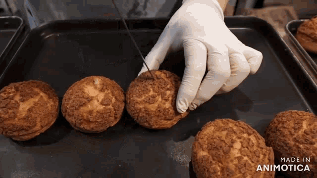a person is cutting a cookie on a tray that says made in animatica on the bottom