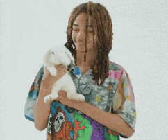 a girl with dreadlocks is holding a stuffed animal in her hands
