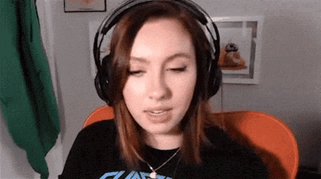 a woman wearing headphones and a necklace is sitting in a chair .