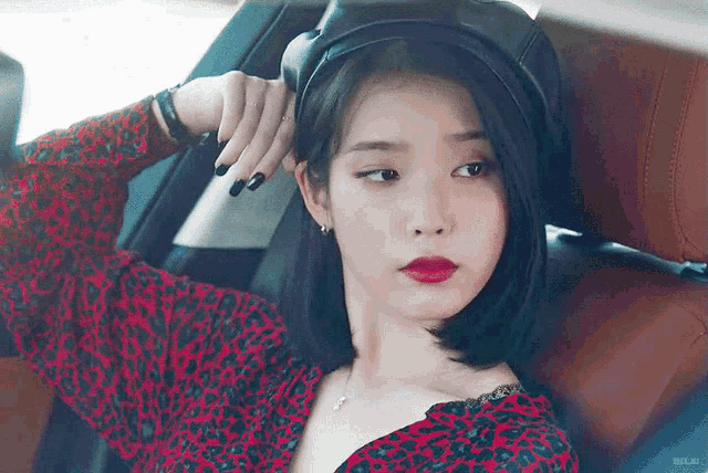 a woman is sitting in the back seat of a car wearing a hat and a leopard print dress .