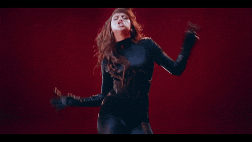 a woman in a black turtleneck is dancing with her hair blowing in the wind
