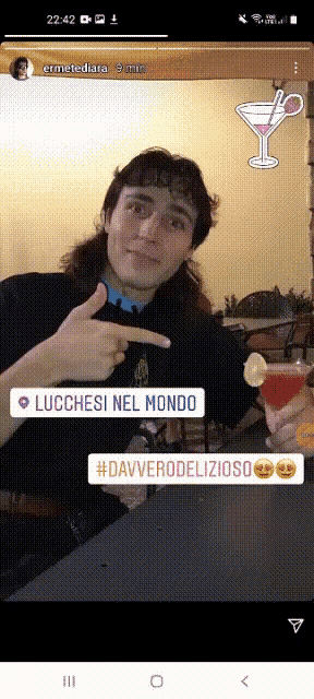 a man sitting at a table with a drink in his hand pointing to a place called lucchetti nel mondo