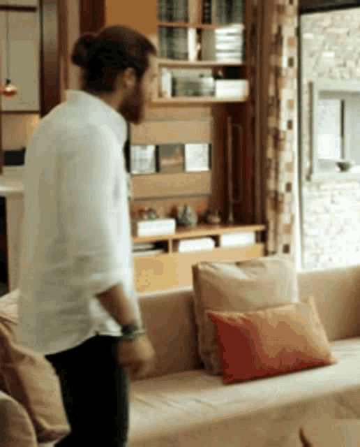 a man standing in front of a couch with a red pillow on it