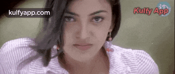 a close up of a woman 's face with a striped shirt on looking at the camera .
