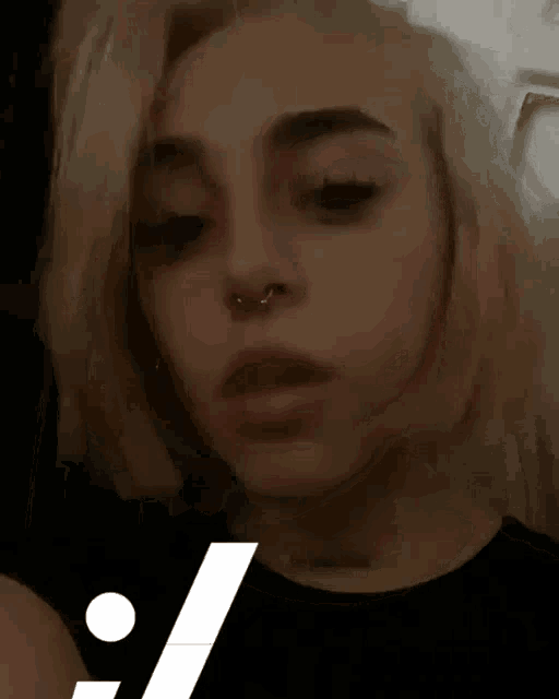 a close up of a woman 's face with a nose ring and a black shirt .