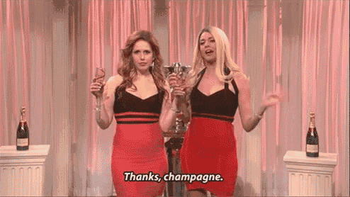 two women in red dresses are standing next to each other holding champagne glasses .