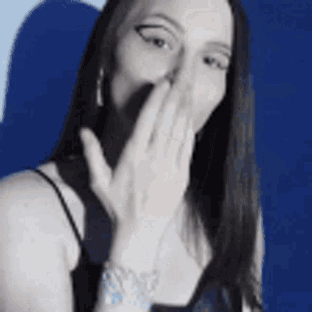 a woman is covering her mouth with her hand while wearing a watch .