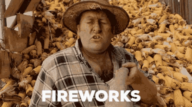 a man in a cowboy hat is standing in front of a pile of corn and the word fireworks is on the bottom