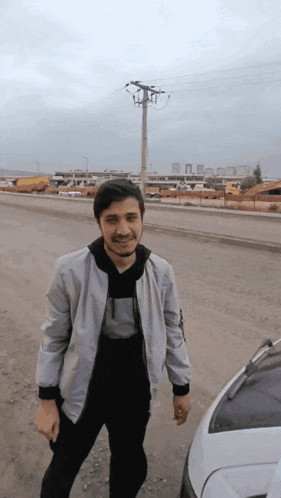 a man in a white jacket stands in front of a white car