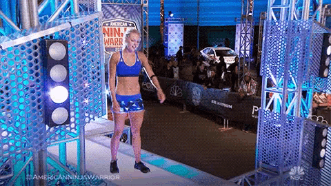 a woman is standing in front of a sign that says ninja warrior