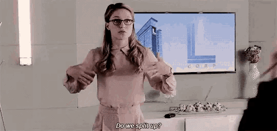 a woman wearing glasses is standing in front of a television and talking to a man in a room .