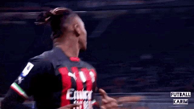 a soccer player wearing a fly emirates jersey stands with his hands folded