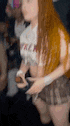 a woman in a skirt is holding a remote control in her hand .