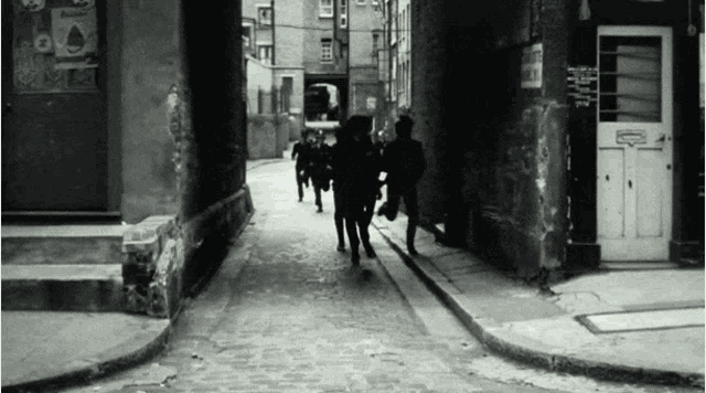 a black and white photo of people running down a street