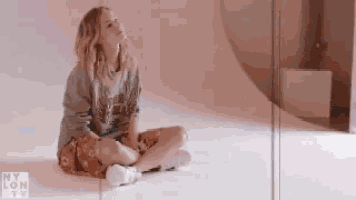 a woman is sitting on the floor with her legs crossed and looking up .