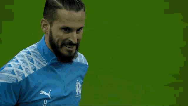 a man with a beard is wearing a blue shirt with a puma logo on it
