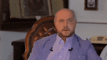 a man with a beard is sitting in a chair with a microphone in his mouth .