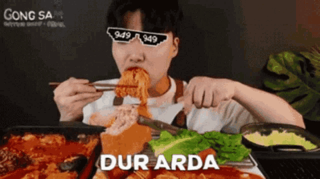 a man wearing sunglasses is eating noodles with chopsticks and the word dur arda is on the bottom