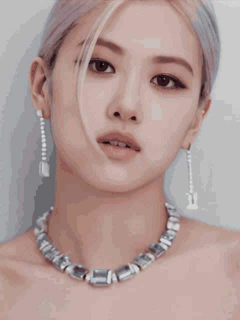 a woman wearing a necklace and earrings has the number 21 on her earring