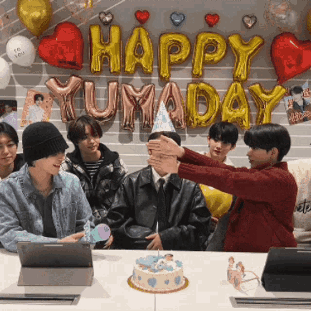 a group of people sitting at a table with balloons that say happy yuma day