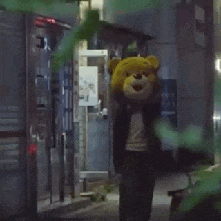 a person wearing a teddy bear costume is walking down a street at night .