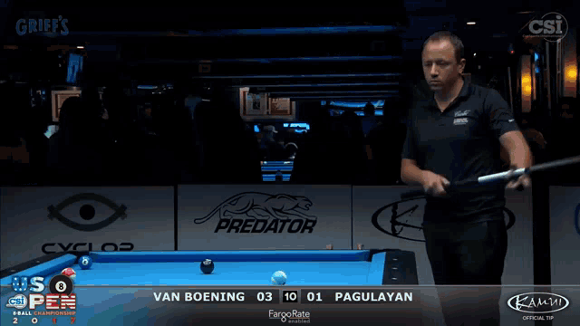 a man playing pool in front of a predator logo