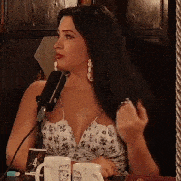a woman sitting in front of a microphone with two mugs on the table with the number 4 on them