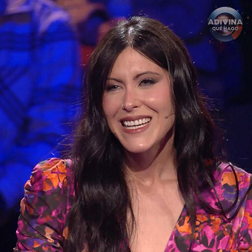 a woman in a floral shirt is smiling in front of a sign that says adivina que hago