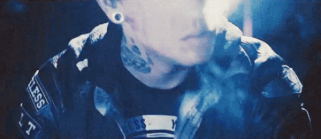 a man with a tattoo on his neck and ear is wearing a black jacket and a black shirt .