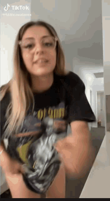 a woman wearing glasses and a black t-shirt with the word colored on it