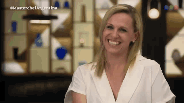 a woman in a white shirt is smiling in front of a masterchef argentina logo