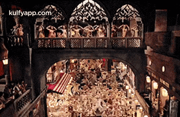 a group of people are standing on a bridge in a building .