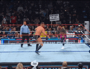 a man in a wrestling ring holding a sign that says gunther is my champion