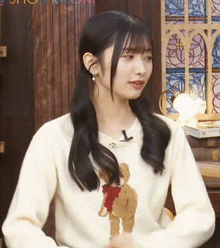 a young woman wearing a white sweater with a teddy bear on it