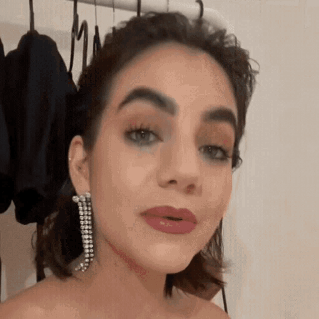 a close up of a woman 's face wearing earrings and lipstick .