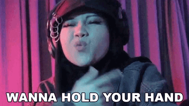 a woman wearing headphones says " wanna hold your hand " while blowing a kiss