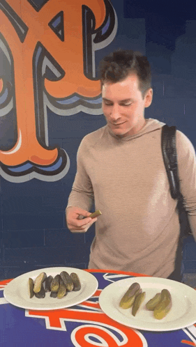 a man eating pickles in front of a wall that has the letter r on it