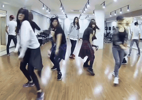 a group of people are dancing in a room with a wooden floor