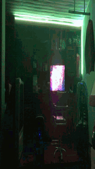 a dark room with a tv on the wall and a pizza box on the floor