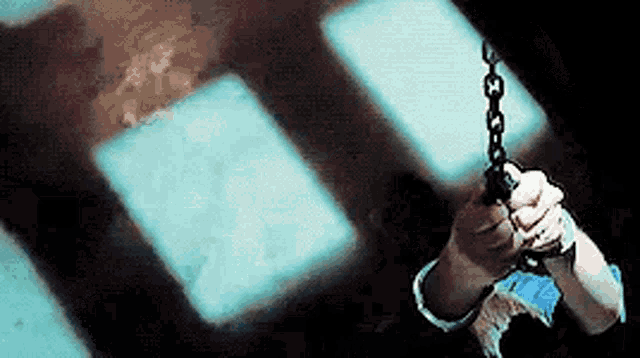 a person is holding a chain in their hand in front of a window .