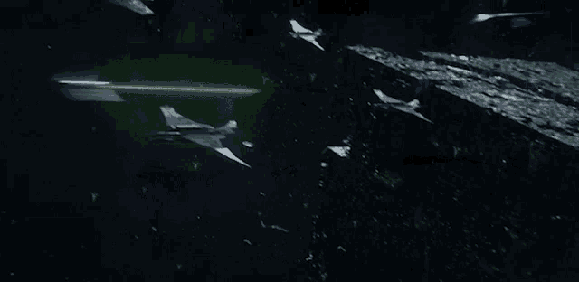 a group of fighter jets are flying through space with a green light in the background