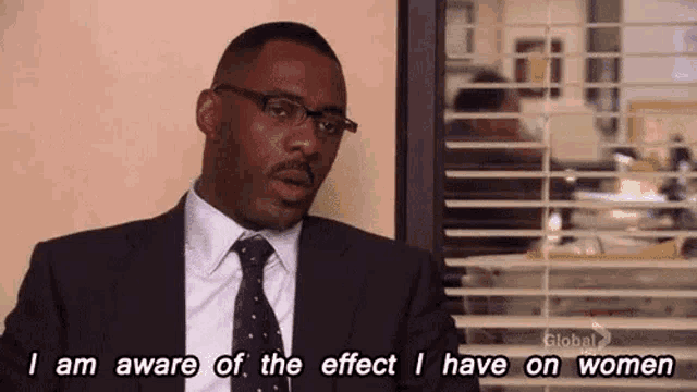a man in a suit and tie is sitting in front of a window and talking about the effect he has on women .