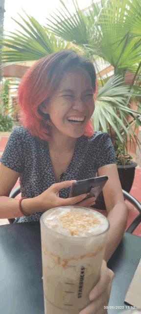 a woman holding a starbucks drink and a cell phone
