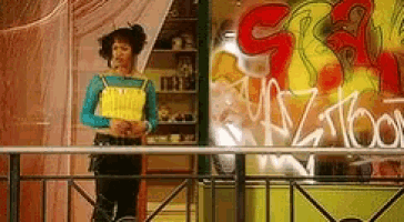 a woman stands in front of a window with graffiti on it that says ' nz toon '