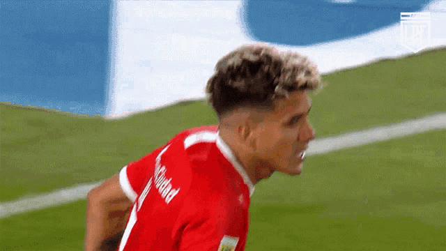 a soccer player wearing a red jersey with the word ciudad on the back