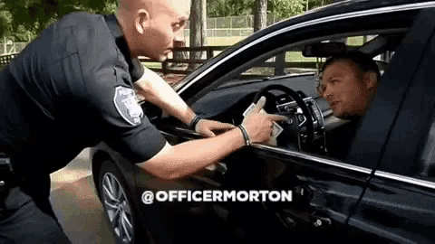 a police officer is giving a ticket to a man in a car