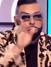 a man with a beard wearing sunglasses and a suit is making a funny face .
