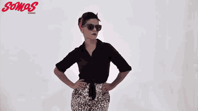 a woman wearing sunglasses stands in front of a white background that says somos