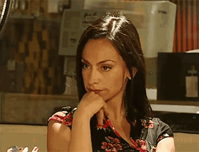 a woman sitting at a table with her hand to her chin